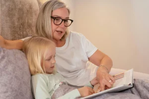 Woman reading a bedtime story to a young girl in bed