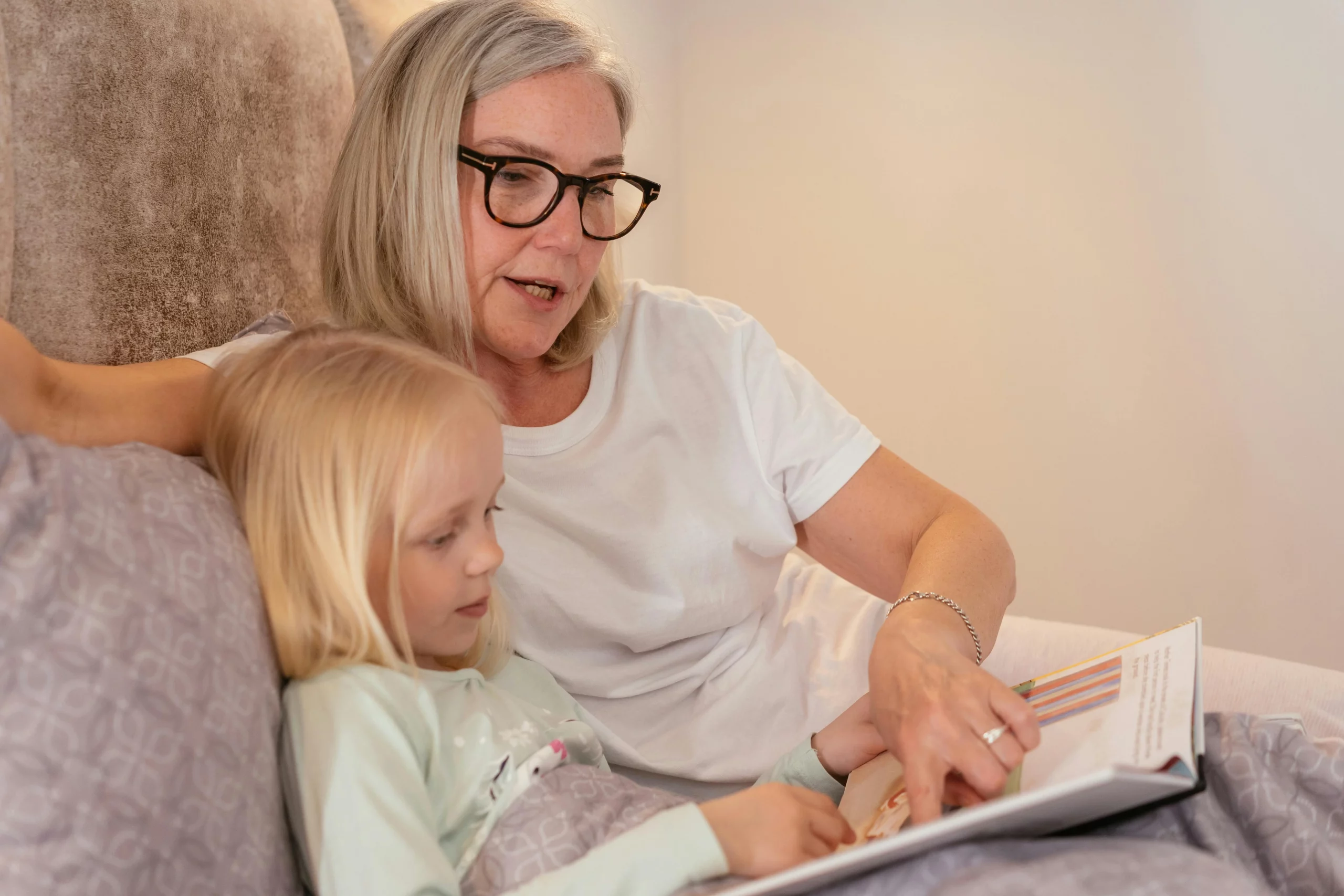 Woman reading a bedtime story to a young girl in bed